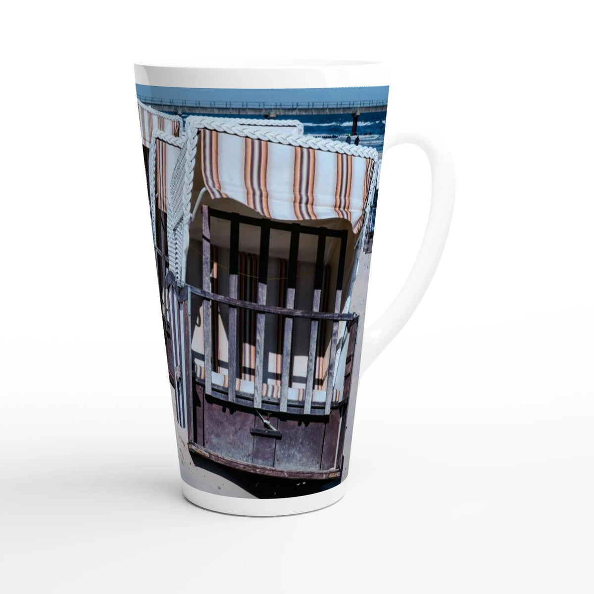 Personalisierbare weiße Latte-Tasse mit ca. 440 ml Fassungsvermögen und maritimer Strandkorb-Fotografie. Die Aufnahme zeigt gestreifte Strandkörbe, dunkle Holzelemente und hellen Sand.