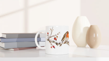 Breiter verschneiter Zweig mit Rotkehlchen, roten Hagebutten, kahlen Seitentrieben und feinen winterlichen Aquarellspritzern