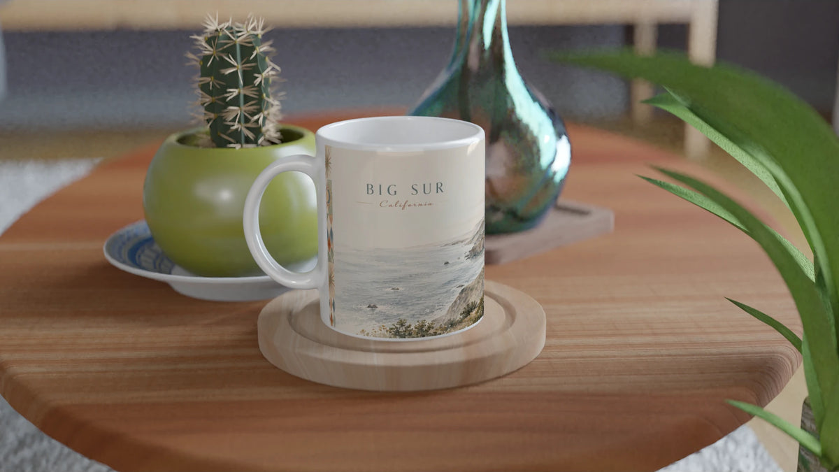 Big Sur California Tasse 0,33 l mit heller Küstenillustration in einem minimalistischen Wohnambiente neben gestapelten Büchern und cremefarbenen dekorativen Vasen