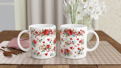Geschenkidee für ein Brautpaar: Keramiktasse mit Eheringen und Rosen im Aquarellstil. Herzsymbole ergänzen die romantische Gestaltung zur Hochzeit oder Verlobung.