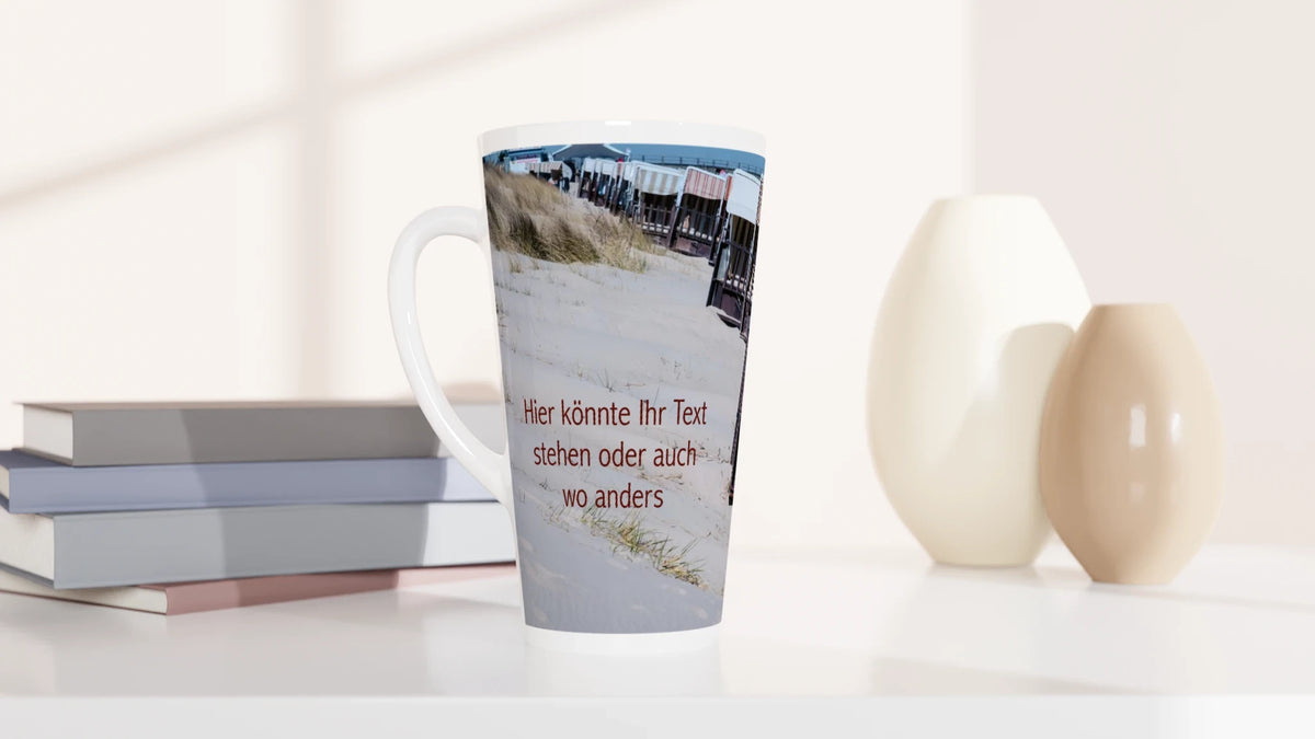Personalisierbare Latte-Tasse mit maritimer Strandfotografie und einem roten Beispieltext auf der Sandfläche. Das Foto kann ersetzt und die Beschriftung individuell gestaltet werden.