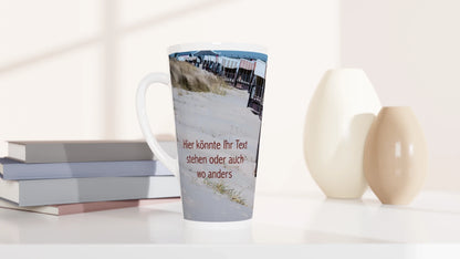 Personalisierbare Latte-Tasse mit maritimer Strandfotografie und einem roten Beispieltext auf der Sandfläche. Das Foto kann ersetzt und die Beschriftung individuell gestaltet werden.