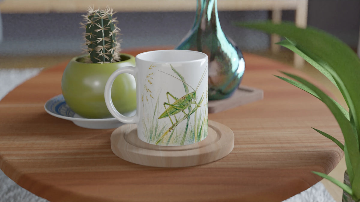 Grüne-Heupferd-Tasse mit großem Heupferd auf einer Seite und sommerlichen Gräsern, Ähren und Dolden auf der anderen.