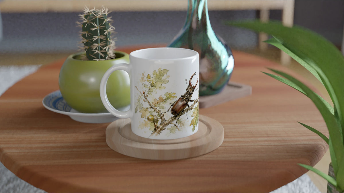 Weiße Hirschkäfer Eichenlaub Tasse 330 ml mit aquarelliertem Käfer- und Eichenmotiv auf einem Holztisch in natürlichem Wohnambiente.