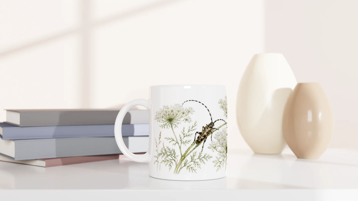 Käfer Wilde Möhre Tasse 330 ml mit feinem Naturmotiv im Aquarellstil in einem hellen minimalistischen Wohnambiente mit Büchern und Vasen.