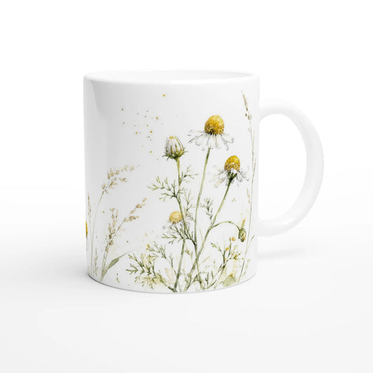 Weiße Keramiktasse mit zarter Kamillenwiese aus weißen Blüten, warmgelben Blütenmitten und locker gemalten Wiesengräsern.
