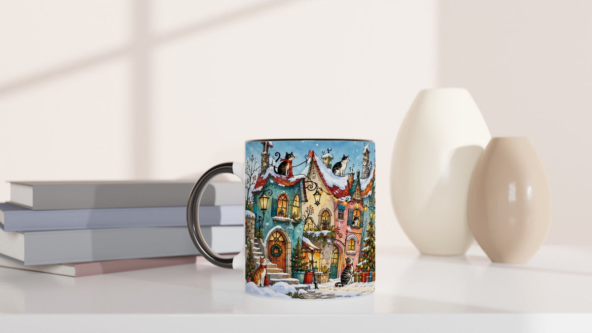Katzen und Weihnachtsbaum in einem verschneiten Winterdorf als Motiv einer festlichen Keramiktasse. Die Dorfhäuser und winterlichen Details verleihen dem Design einen märchenhaften Charakter.