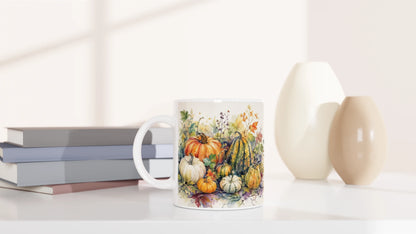 Herbstliche Tasse mit weißen, grünen und gemusterten Zierkürbissen zwischen Blättern, Ranken und kleinen Blüten
