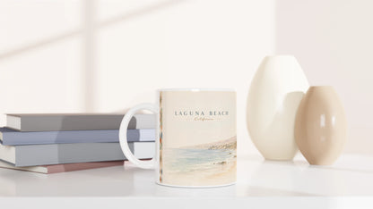 Laguna Beach California Tasse 0,33 l mit heller Pazifikillustration in einem minimalistischen Wohnambiente neben gestapelten Büchern und cremefarbenen dekorativen Vasen