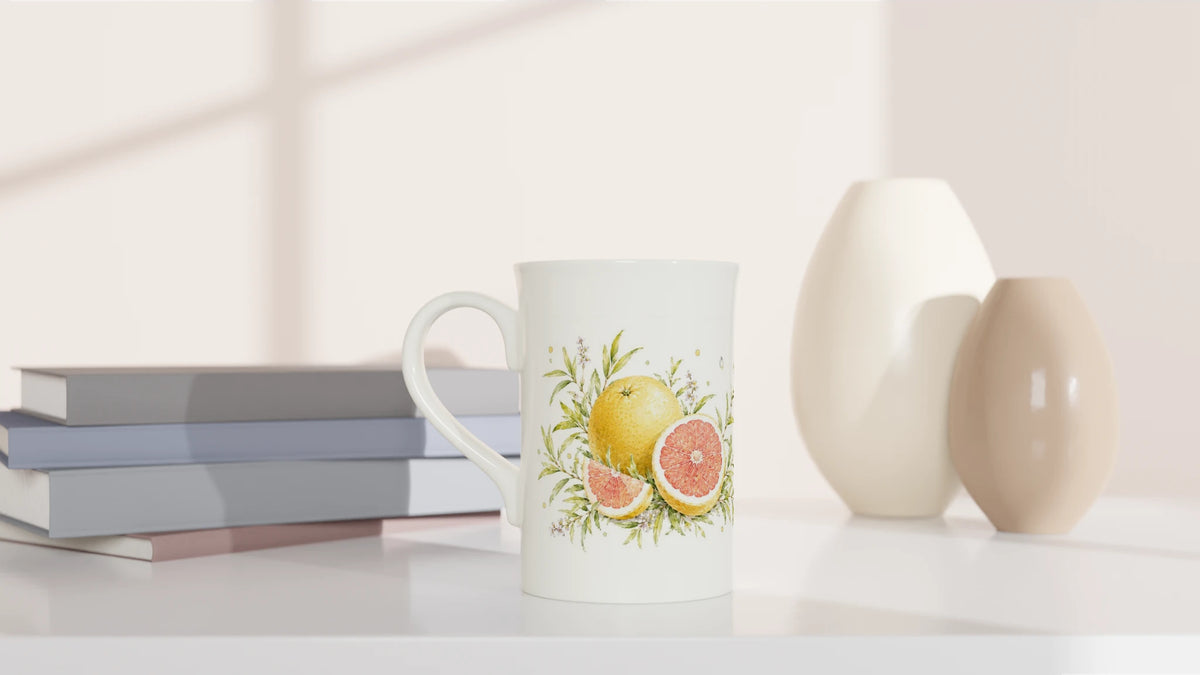 Weiße Tasse mit Pampelmuse und Blattwerk in sonnigen Gelb-, Rosé- und Grüntönen mit viel Weißraum