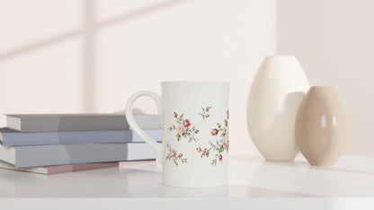 Detailreiche Vintage-Rosenillustration auf einer schlanken weißen Porzellantasse. Kleine Knospen, zarte Blütenblätter und grüne Zweige bilden ein harmonisches botanisches Motiv.