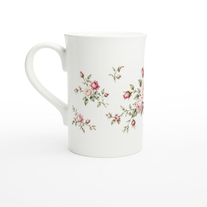 Elegante weiße Porzellantasse mit zartrosa Rosen und feinem Blattwerk. Die zurückhaltende florale Komposition eignet sich für Liebhaber klassischer Blumenillustrationen und nostalgischer Designs.