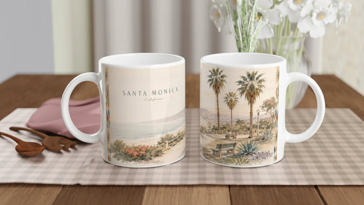 Seitliche Ansicht der Santa Monica California Tasse mit aquarelliertem Küstenweg, Holzgeländer, Pazifik, hellem Strand, Bergen und einer Parkbank unter kalifornischen Palmen