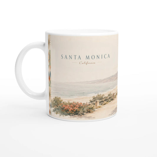 Santa Monica California Keramiktasse mit sanftem Pazifik-Aquarell auf einem Holztisch in einem Wohnambiente mit kleinem Kaktus, Glasvase und grüner Pflanze