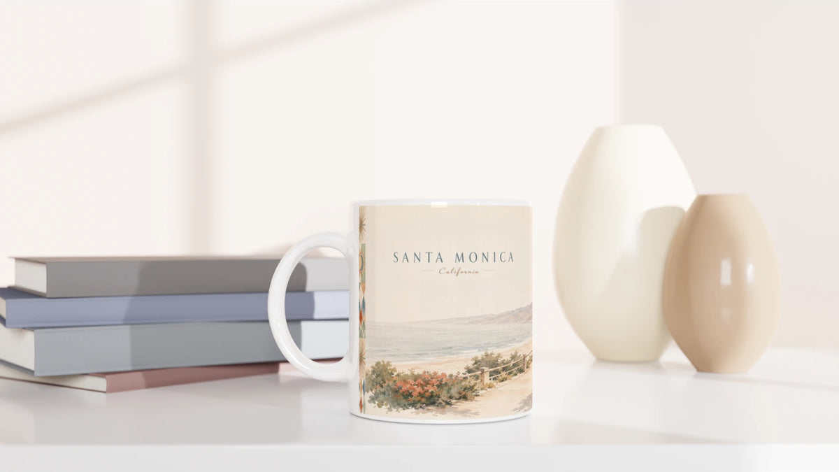 Zwei Ansichten der Santa Monica California Tasse zeigen auf einer Seite Pazifik und SANTA MONICA Schriftzug sowie auf der anderen Palmen, Parkbänke, Agaven und zwei sitzende Personen