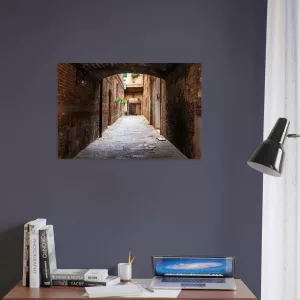 Aluminiumbild mit historischer, schmaler Gasse in Siena unter einem dunklen Torbogen, warmen Backsteinwänden und hellem Ausgang im Hintergrund.
