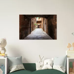 Aluminiumbild mit historischer, schmaler Gasse in Siena unter einem dunklen Torbogen, warmen Backsteinwänden und hellem Ausgang im Hintergrund.