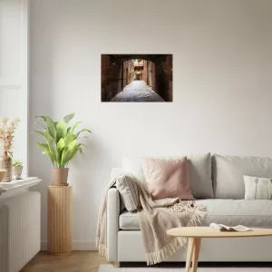 Aluminiumbild mit historischer, schmaler Gasse in Siena unter einem dunklen Torbogen, warmen Backsteinwänden und hellem Ausgang im Hintergrund.